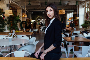 Portrait of a young cute brunette girl business in the interior hipster cafes. Long hair.