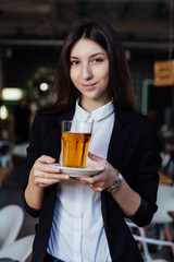 young cute brunette girl business in the interior hipster cafes holding a glass of tea.