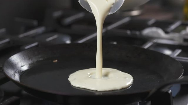 Slow motion of preparin blini or crepes batter pouring on hot pan, 180fps prores footage