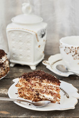 Slice of layer cake with chocolate shavings and a cup of tea.