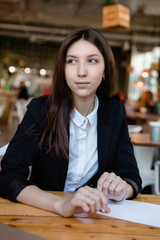 Fototapeta na wymiar Portrait of a young sweet pretty girl with long brunette hair business. sitting at a wooden table