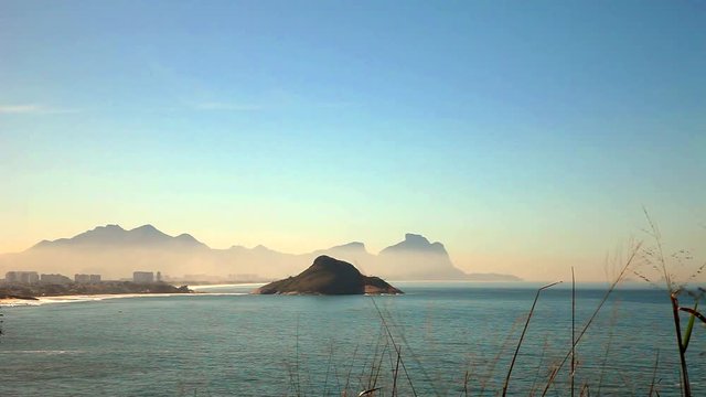 Grumari Beach is a good spot for surf and relaxes in Rio de Janeiro. View of an island with downtown on the background.