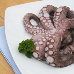 Polipo fresco con prezzemolo su piatto su tavolo di legno