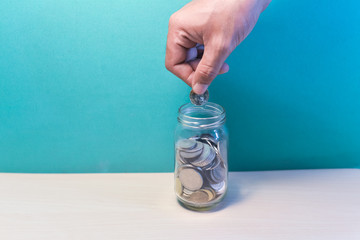 Saving Concept.hand putting coin in glass jar.