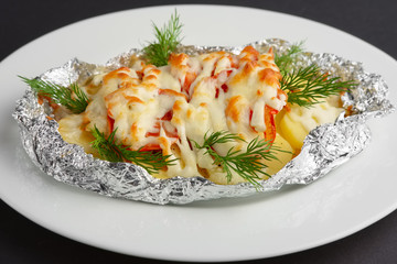 Closeup view of fried in foil sea fish and potato with paprica and cheese