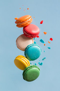 Different types of macaroons in motion falling on light blue background. 