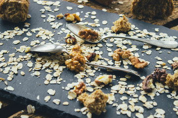 Two upside down vintage spoons different shapes on the slate Board, scattered with oatmeal, walnuts and bread crumbs. Closeup