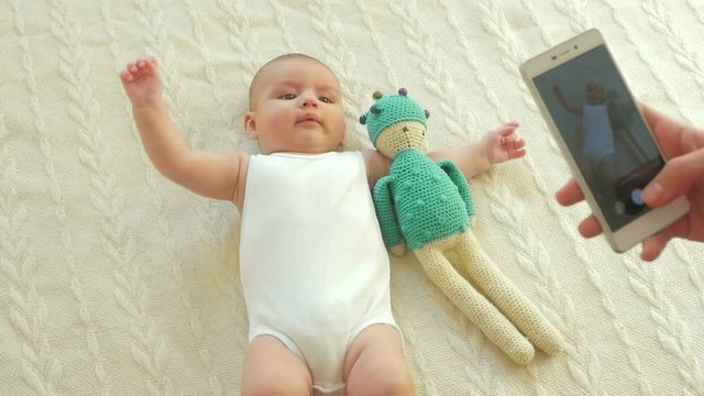 Mother with mobile smart phone pictures of Cute 2-month-old baby boy.