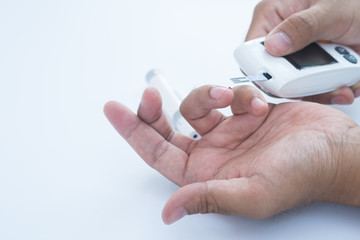 Close up of asian man's  hands using lancet on finger to check blood sugar level by glucose meter, Healthcare medical and check up, diabetes, glycemia, and people concept