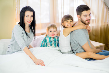 family posing on the bed in the hotel