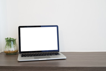 office table with blank screen laptop and garden plant garden on cement wall background, view from front office table.