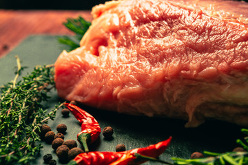 raw pork meat with spices on slate stone kitchen board
