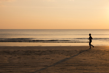 Woman running on the beach at sunset, healthy lifestyle