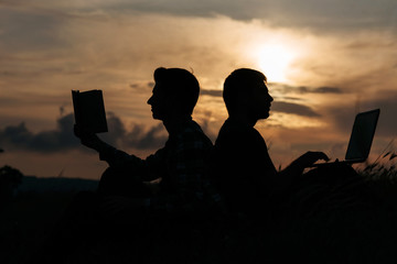Fototapeta na wymiar Silhouette of two man working with book and notebook at sunset