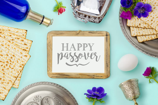 Passover holiday concept with wine bottle, matzoh and photo frame over mint background. Top view from above