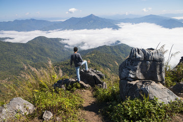 Fototapeta premium man standing on the cliff and looking at the valley and mountains in the daylight
