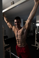 Fototapeta na wymiar Muscular Man Flexing Abdominal Muscles In Gym