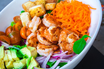 Shrimp salad with cherry tomatoes and natural condiment in a white bowl.
