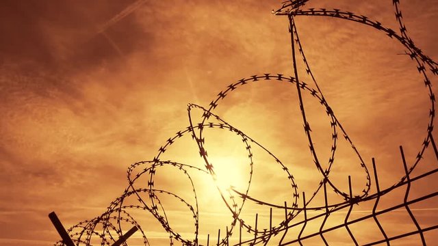 Prison barbed wire fence at sunset