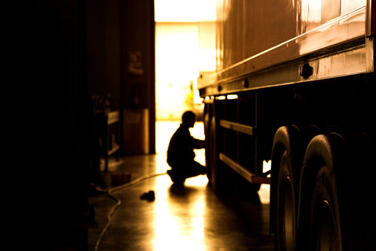 silhouette blur automobile mechanic checking truck in the garage, selective focus and cool tone photograph.
