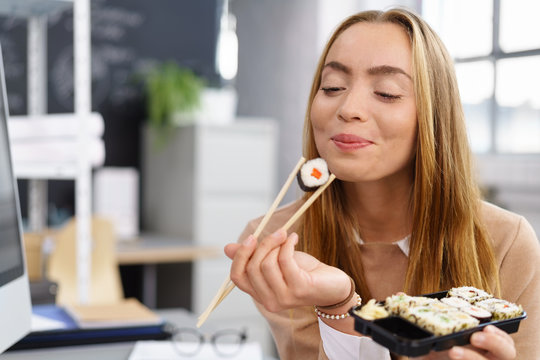 frau genießt sushi in der pause am arbeitsplatz