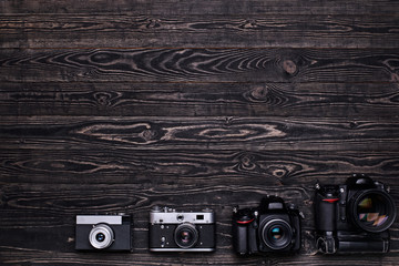 Top view photo of cameras on dark wooden background/Old retro and modern digital cameras on dark wooden table