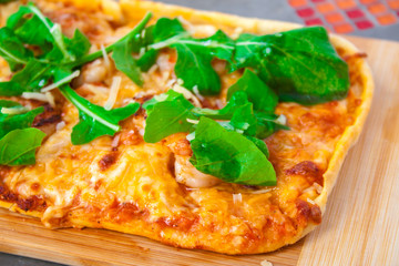 Homemade pizza with basil and cheese with organic tomato on a wooden board.