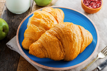 Croissant with fruit jam and fresh milk for healthy breakfast. Delicious French meal on a table. Top view close-up shot.