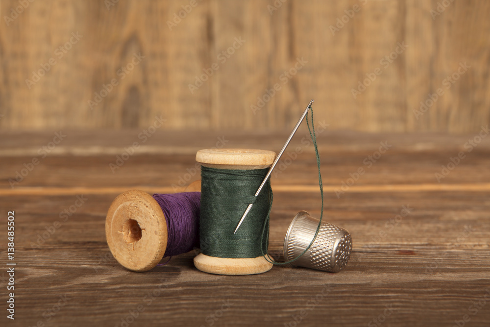 Wall mural On the wooden shelves are two spools of thread with a needle and thimble. Close-up