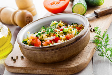 Delicious Israeli couscous Ptitim with vegetables on a white wooden table. Cooking of healthy vegetarian food for the meal. Traditional Moroccan cuisine.