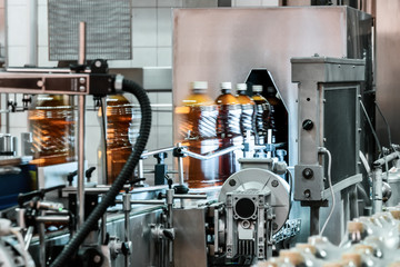 Plastic bottles filled with beer on the conveyor of the filling machine.