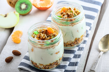 Granola with yogurt and fruits in a rustic jar. Delicious healthy American food for breakfast. Traditional US snack. Close-up shot.