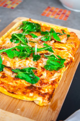 Pizza with basil, cheese and tomato on a wooden board.