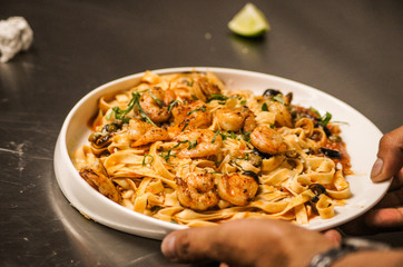Pasta with fresh sauce and shrimps on a white plate background.