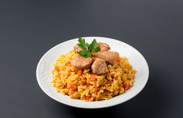 Rice with meat on a white plate. Pilaf on gray background