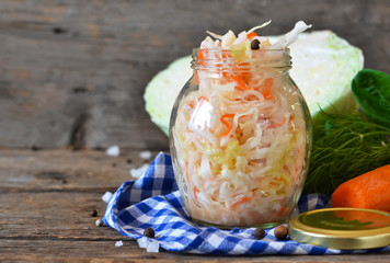 Salad of sauerkraut and carrots in a jar on a wooden background