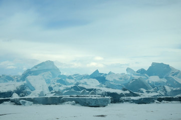 ice hummocks on the northern shore of Olkhon Island on Lake Baikal. Transparent blocks of crystal clear ice crawl ashore. Colorful refraction of rays of rising sun. Ice Storm. Photo partially tinted.