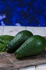 Green ripe avocado with leaves on granite plank