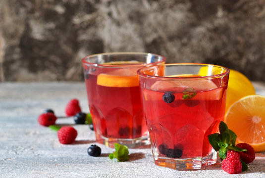 Cold berry drink with lemon and mint on a concrete background