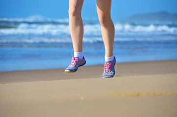 Fitness and running on beach, woman runner legs in shoes on sand near sea, healthy lifestyle and sport concept
