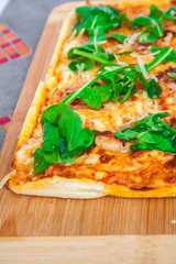 Pizza with basil, cheese and tomato on a wooden board.