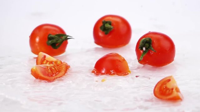 
Slices of Ripe Tomato Falls on the Table, Splashing Drops. Slow Motion.
