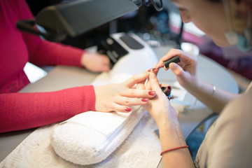 Obraz na płótnie Canvas Woman hands in a nail salon receiving a manicure by a beautician
