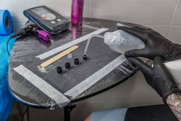 Hands of a tattoo artist woman filling a few small ink cartridges