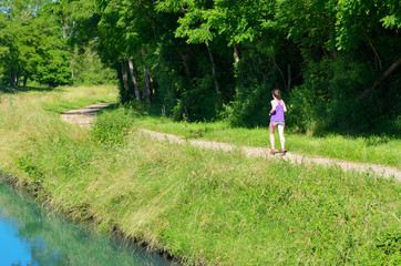 Active woman runner jogging near canal river, outdoors running, sport, fitness and healthy lifestyle concept
