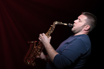Fototapeta na wymiar Bearded saxophonist playing inspired on saxophone isolated on a black background