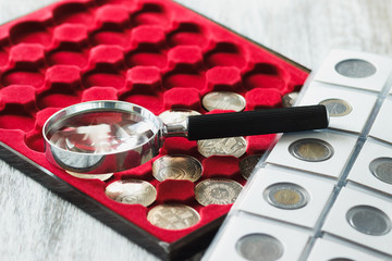 Different collector's coins in the box for coins and a magnifying glass