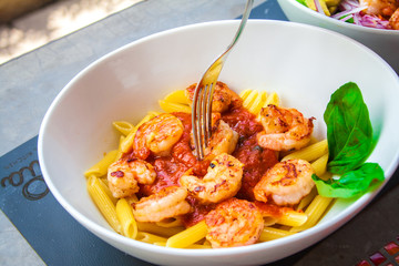 Pasta with fresh sauce and shrimps on a white plate background.