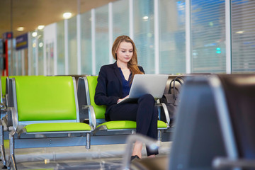 Woman in international airport terminal, working on her laptop
