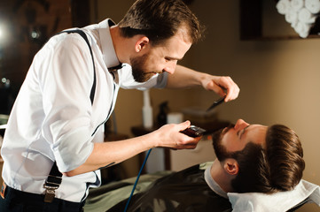 Obraz premium Master cuts hair and beard of men in the barbershop